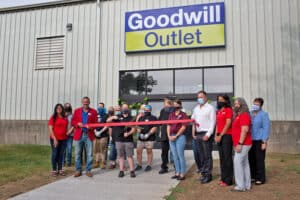 Community and team members celebrate the grand opening of the Goodwill Outlet Store in Cedar Rapids with a ribbon cutting.