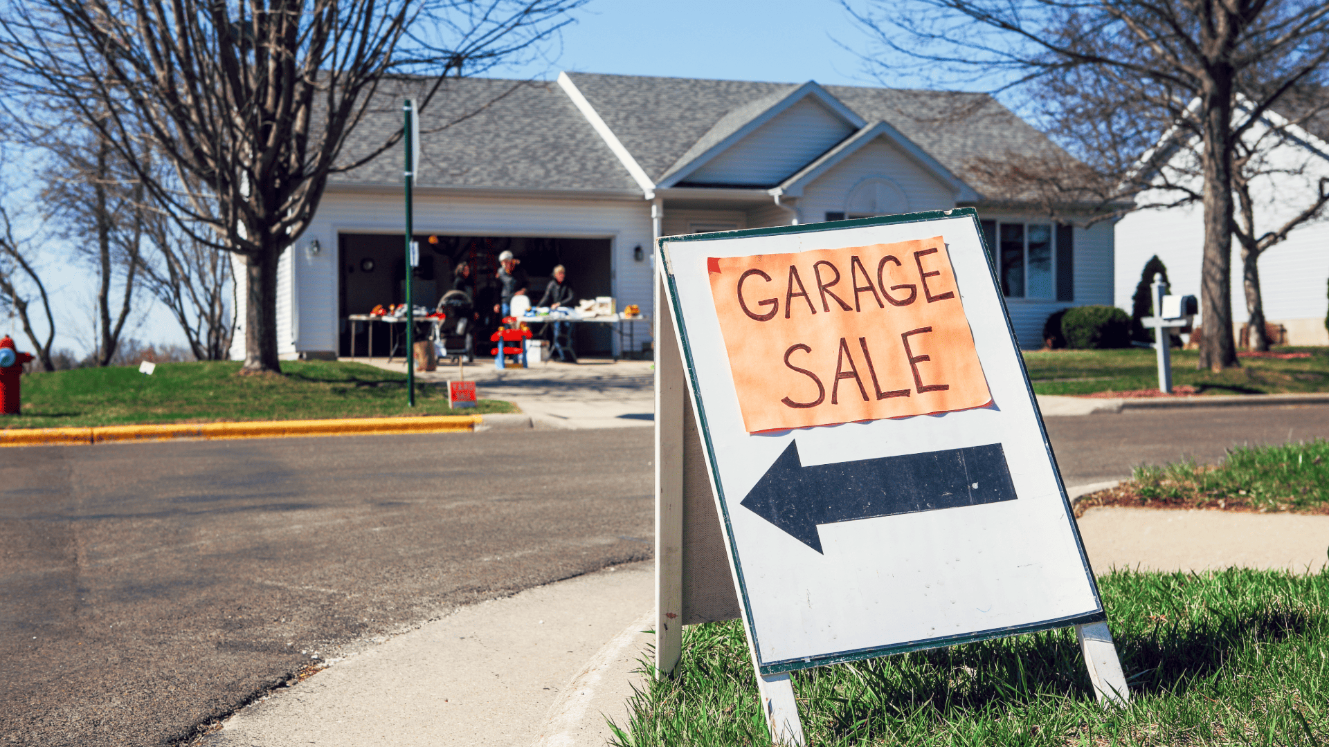A garage sale sign with a sale in the background.