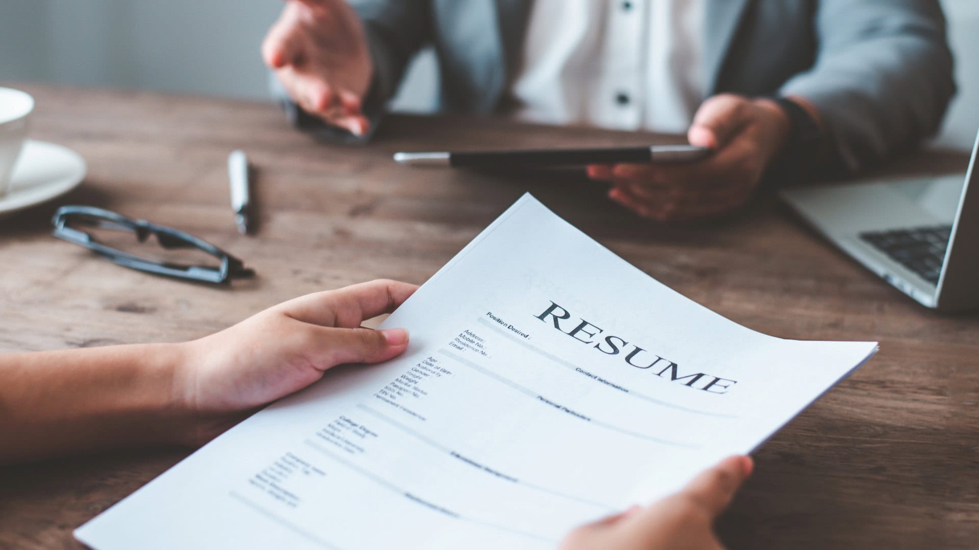 Resume being passed across a wooden desk